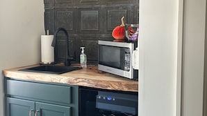 A kitchen with a wooden countertop, a microwave, a sink with a paper towel holder, and a dishwasher. - Westphalia Inn (Westphalia)