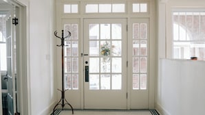A hallway with a white door, a coat rack, and a patterned floor. - Westphalia Inn (Westphalia)
