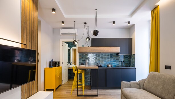 A modern kitchen with a central island, a dining area with a yellow stool, and a living room with a sofa. - Tribunali Trendy Apartment by Wonderful Italy (Naples)