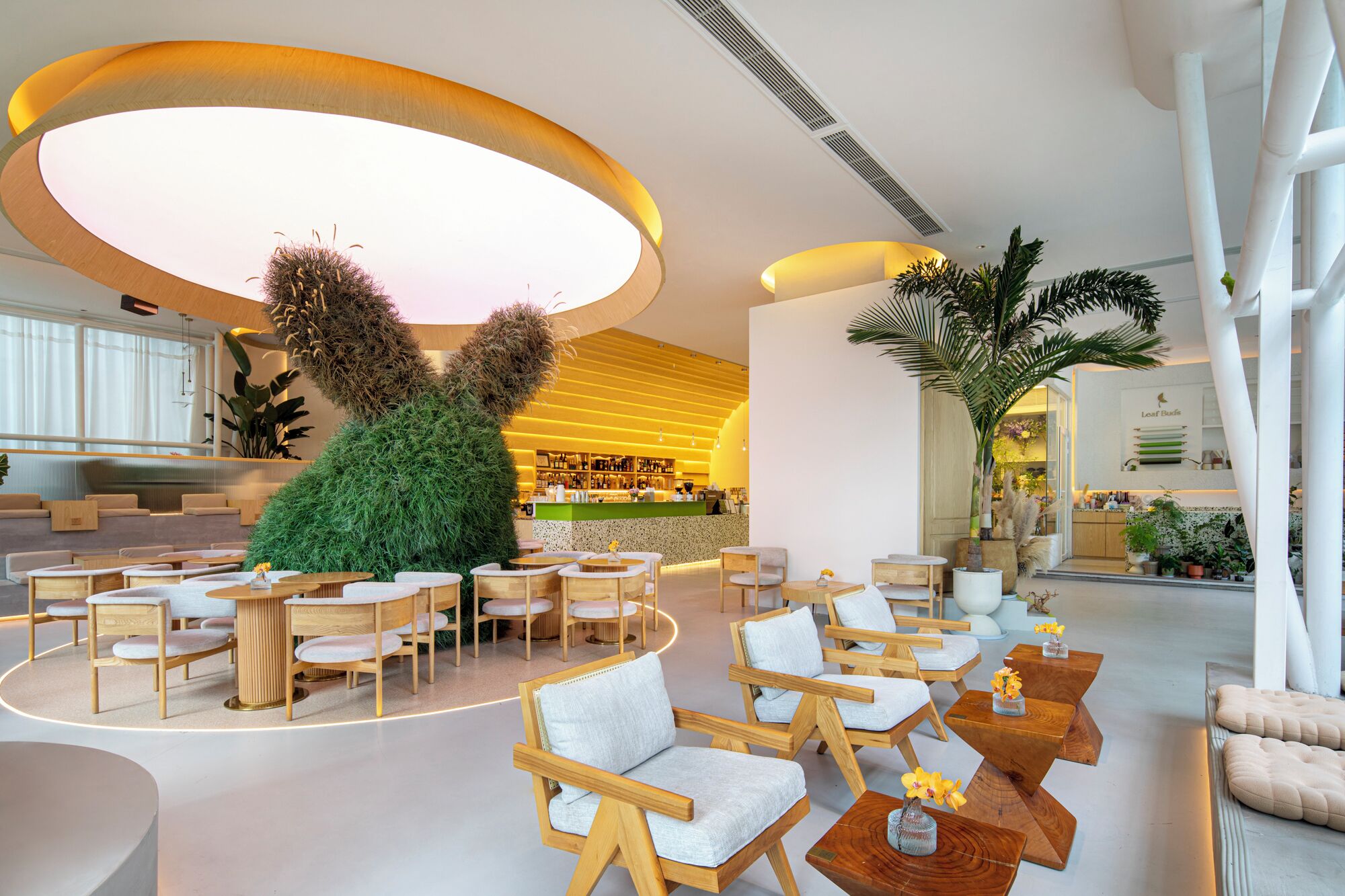 A modern interior with a central seating area, a bar, and a large plant sculpture.