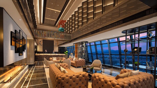 Eine geräumige Lobby mit hoher Decke, einem Empfangsbereich und einer Sitzecke mit komfortablen Sofas.