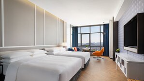 Ein Hotelzimmer mit zwei Betten, einem Fernseher, einem großen Fenster mit Aussicht und Holzboden.