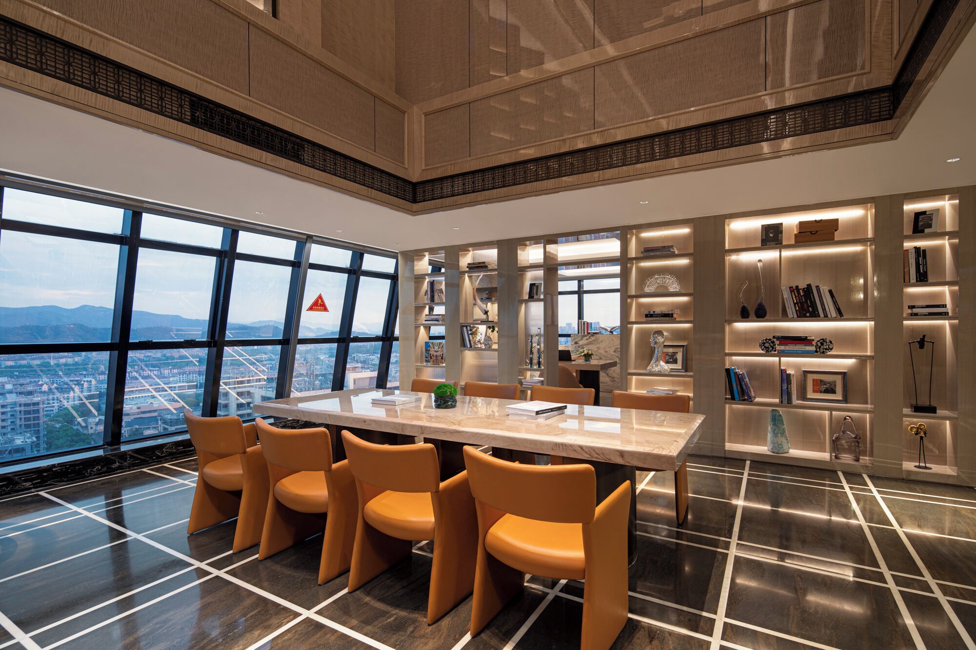 A modern dining area with a large table and chairs, surrounded by bookshelves and decorative items.