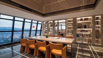 Un espace repas moderne, doté d’une grande table et de chaises, entouré d’étagères et d’objets décoratifs.