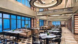 Ein geräumiges Restaurant mit hohen Decken, großen Fenstern und einem Schachbrettmuster auf dem Boden.