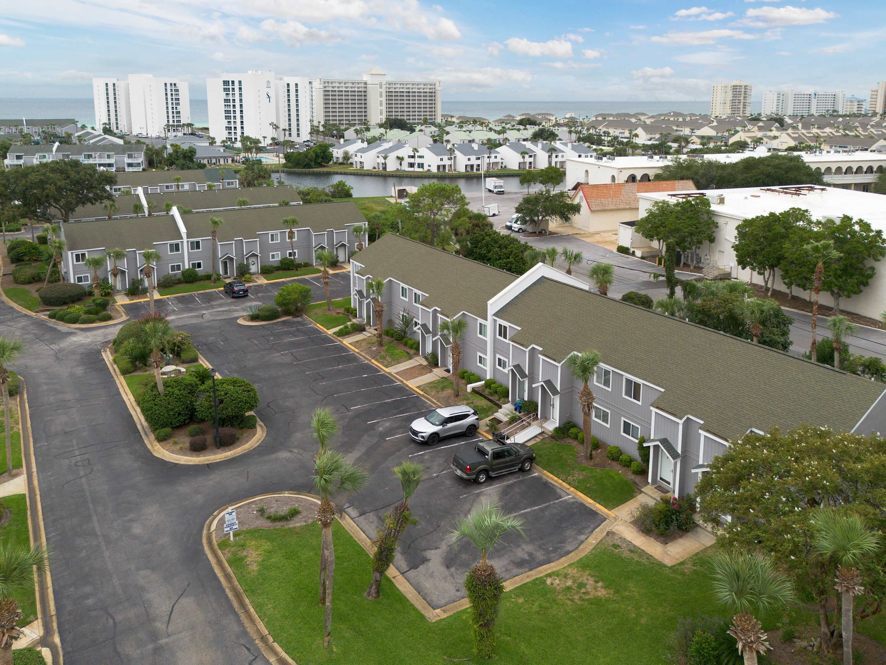 A residential area with apartment buildings, a parking lot, and a view of the ocean.