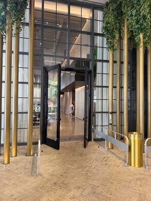 Une entrée moderne avec une porte en verre, un portail en métal et un sol en briques.