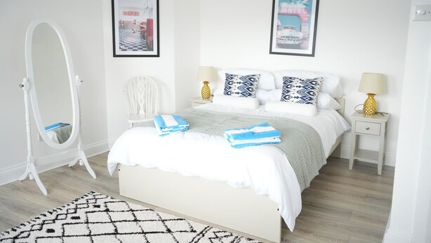 A neatly arranged bedroom with a bed, a vanity with a mirror, and two framed pictures on the wall. - Fun Energetic Oasis in Islington - Sleeps6 (London)