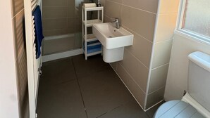 A bathroom with a white sink, a mirror, and a shower area. - Fun Energetic Oasis in Islington - Sleeps6 (London)
