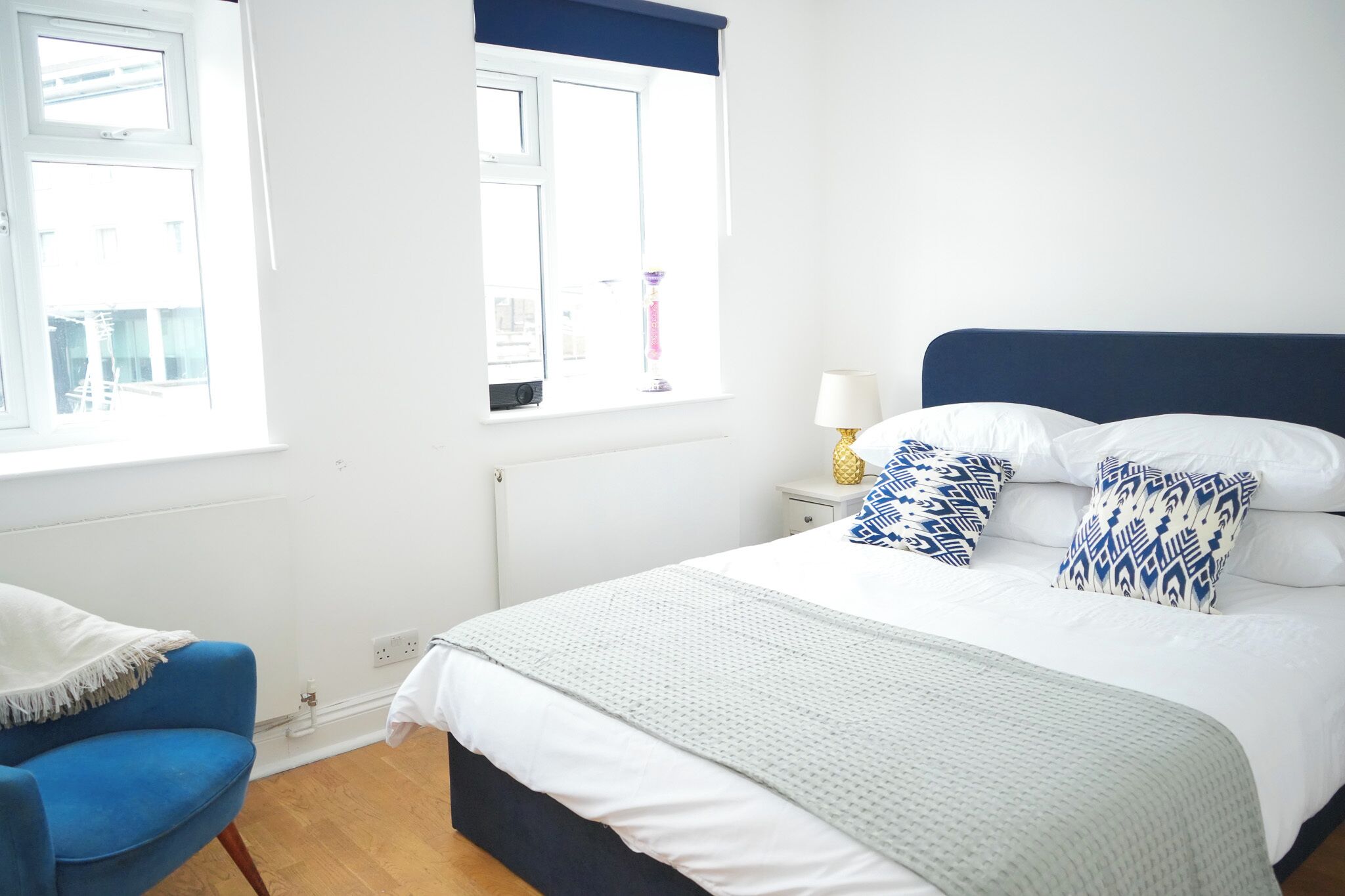 A neatly arranged bedroom with a bed, a chair, and a nightstand.