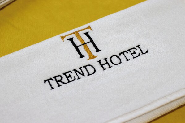 A white towel with the text "TREND HOTEL" and a stylized 'H' logo.