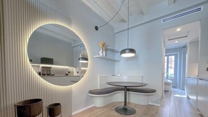 Une cuisine moderne avec un grand miroir rond, un plancher en bois et un coin repas comprenant une table ronde et un banc.