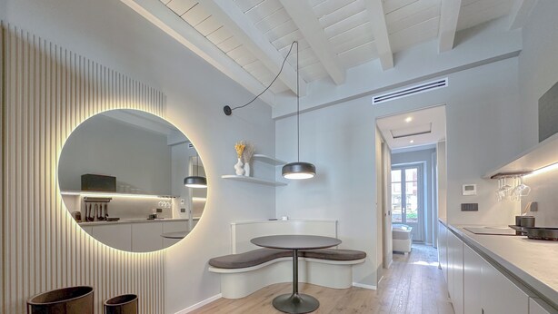 Une cuisine moderne avec une table à manger ronde, des luminaires suspendus et un grand miroir.