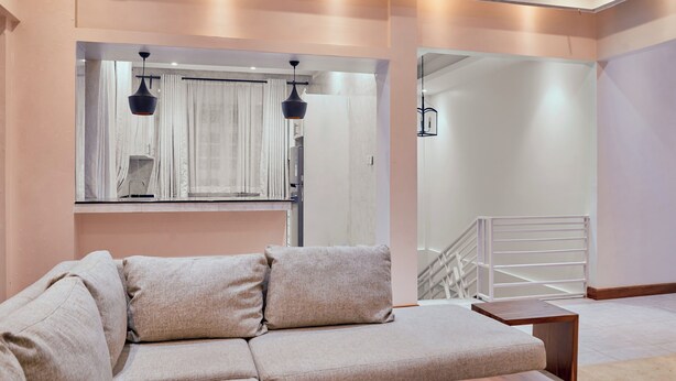 A modern living room with a sectional sofa, a wooden coffee table, and a glass door leading to a staircase. - Kilimanjaro Foothills Getaway (Marangu)