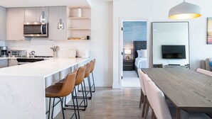 Una cocina moderna con una isla grande, taburetes de bar y un comedor con una mesa larga y sillas.
