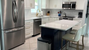 A modern kitchen with white cabinets, stainless steel appliances, a central island, and a sink. - Stroll to the Sea, Steps to the Village!
Boat Docking, Kayaks, Heated Pool & Spa (sarasota)
