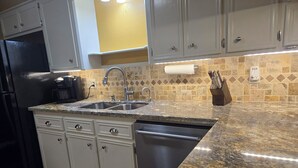 A kitchen with white cabinets, a granite countertop, a stainless steel sink, and a coffee maker. - Clean 2-bd townhome in quiet neighborhood close to all that B/CS offers. (Bryan)