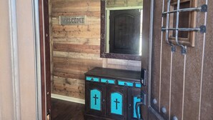 A wooden interior with a 'WELCOME' sign, a dark wooden cabinet with turquoise accents, and a metal gate. - Clean 2-bd townhome in quiet neighborhood close to all that B/CS offers. (Bryan)