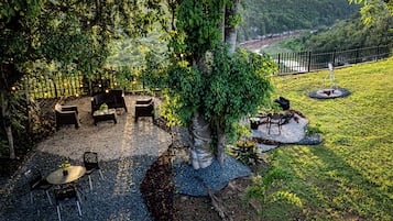 Relax in a serene outdoor space surrounded by lush greenery and scenic views of a river and distant hills.