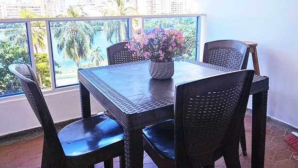 A balcony with a table and chairs, a potted plant, and a view of a city skyline and palm trees. - Apartment on the 4th floor with beautiful views by Parceros Group (Cartagena)