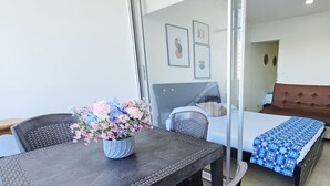A room with a dining table, chairs, a sofa, and a bed. There is a vase with flowers on the table. - Apartment on the 4th floor with beautiful views by Parceros Group (Cartagena)