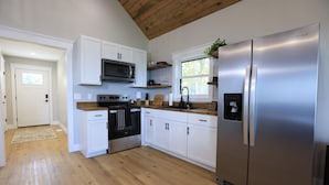 A modern kitchen with white cabinets, stainless steel appliances, and a wooden ceiling. - Stunning view! Hot Tub, Privacy & Relaxation (Raywick)