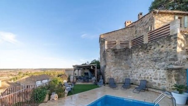 Ein Gebäude aus Stein mit einem Pool und Liegestühlen.