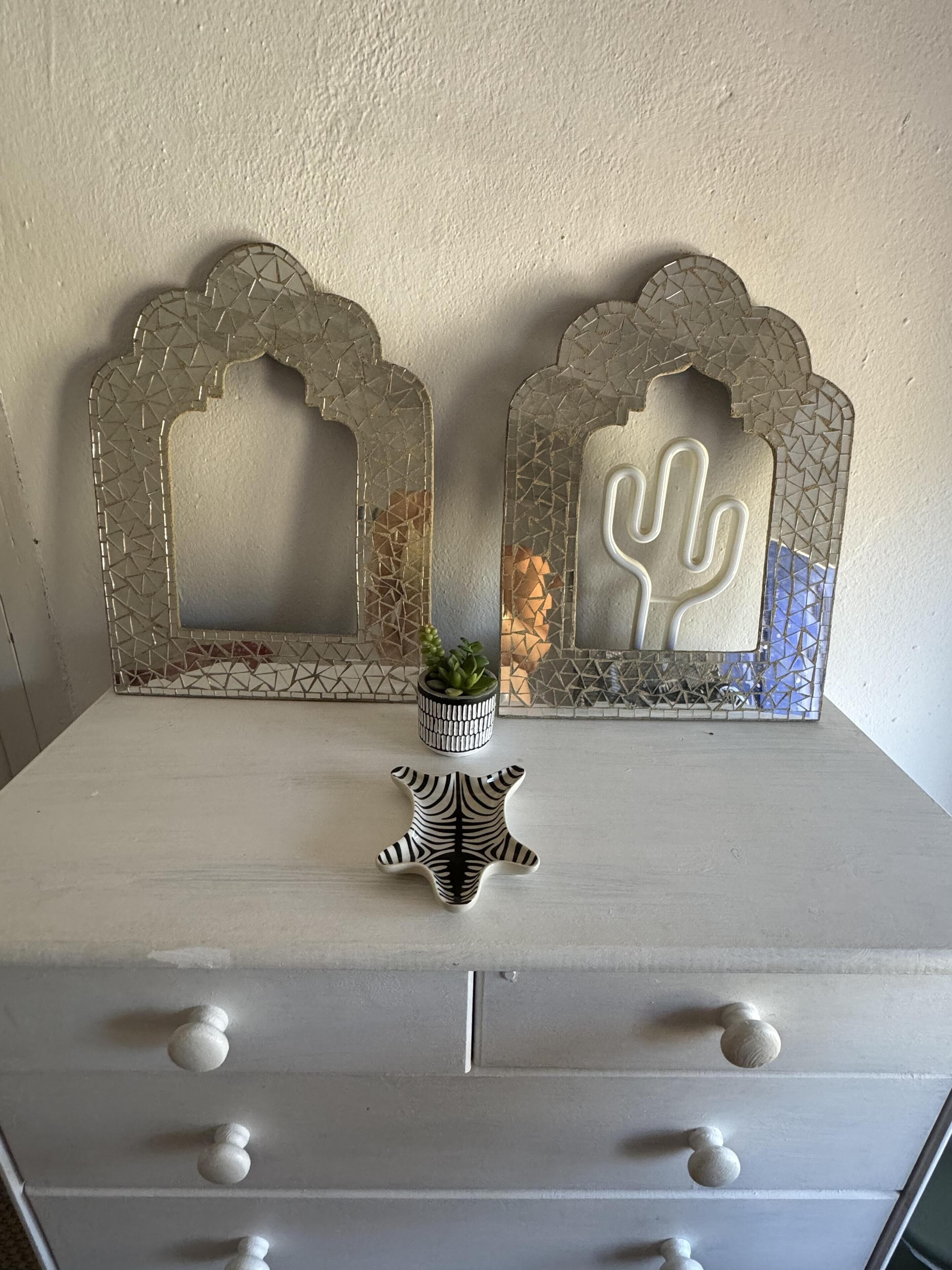 A white dresser with three drawers and a small potted plant on top.