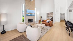 Una sala de estar moderna con chimenea, un sofá, una mesa de centro y un comedor con sillas.