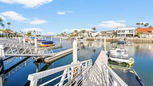 Un puerto deportivo con barcos amarrados, un puente peatonal y edificios residenciales al fondo.