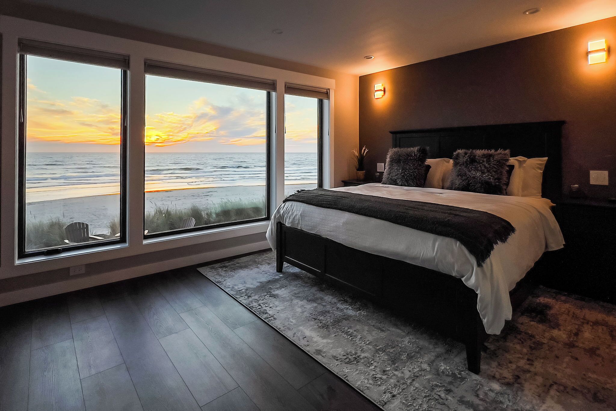 A bedroom with a large bed, a view of the beach, and a modern design.