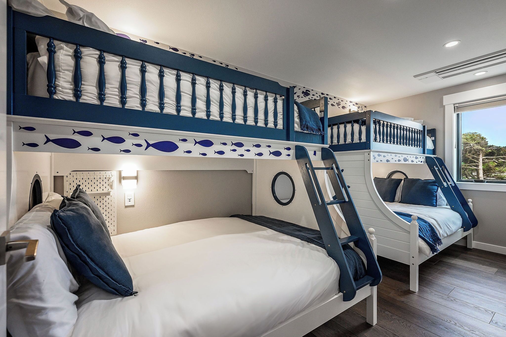 Une chambre avec des lits superposés, dotée d’une fenêtre ronde et offrant une vue sur l’extérieur.