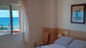 A bedroom with a bed, a nightstand, a lamp, a framed picture, and a window with curtains. - Apartamento de luxe Frontal al mar (Oropesa del Mar)
