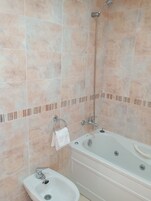 Un baño con baldosas color beige, una bañera, un lavabo y una ducha.