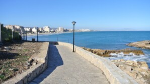 A coastal walkway with a stone railing, leading to the beach. - Apartamento de luxe Frontal al mar (Oropesa del Mar)