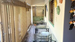 A corridor with a glass table and chairs, a decorative gate, and a wall with colorful bird sculptures. - Suites Boa Viagem (Pirenópolis)