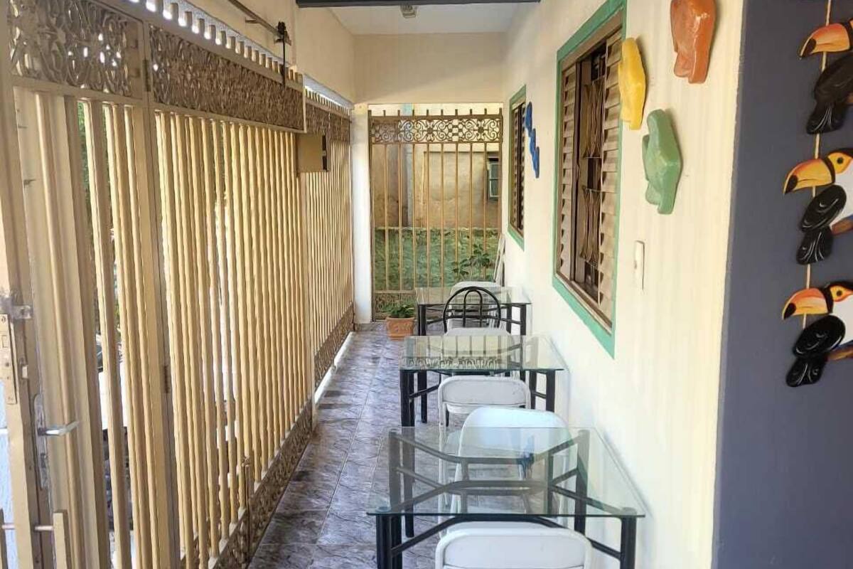 A corridor with a glass table and chairs, a decorative gate, and a wall with colorful bird sculptures.