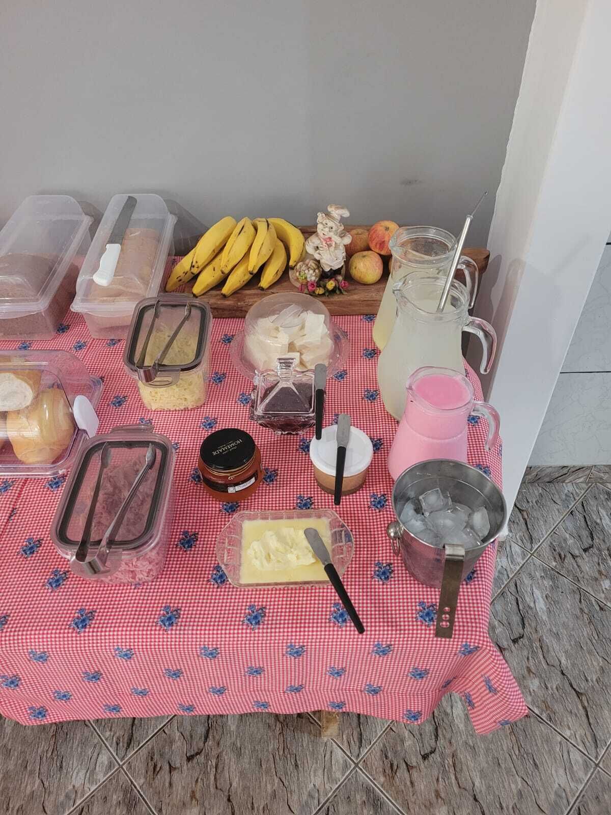 A table with food items and drinks, including bread, butter, jam, and a pitcher of lemonade.