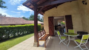 A covered patio with a wooden bench, a table, and two chairs. - This house is no longer available for rent (Moliets-et-Maa)