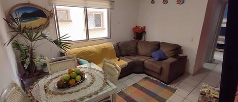A living room with a dining table, a sofa, and a window with blinds.