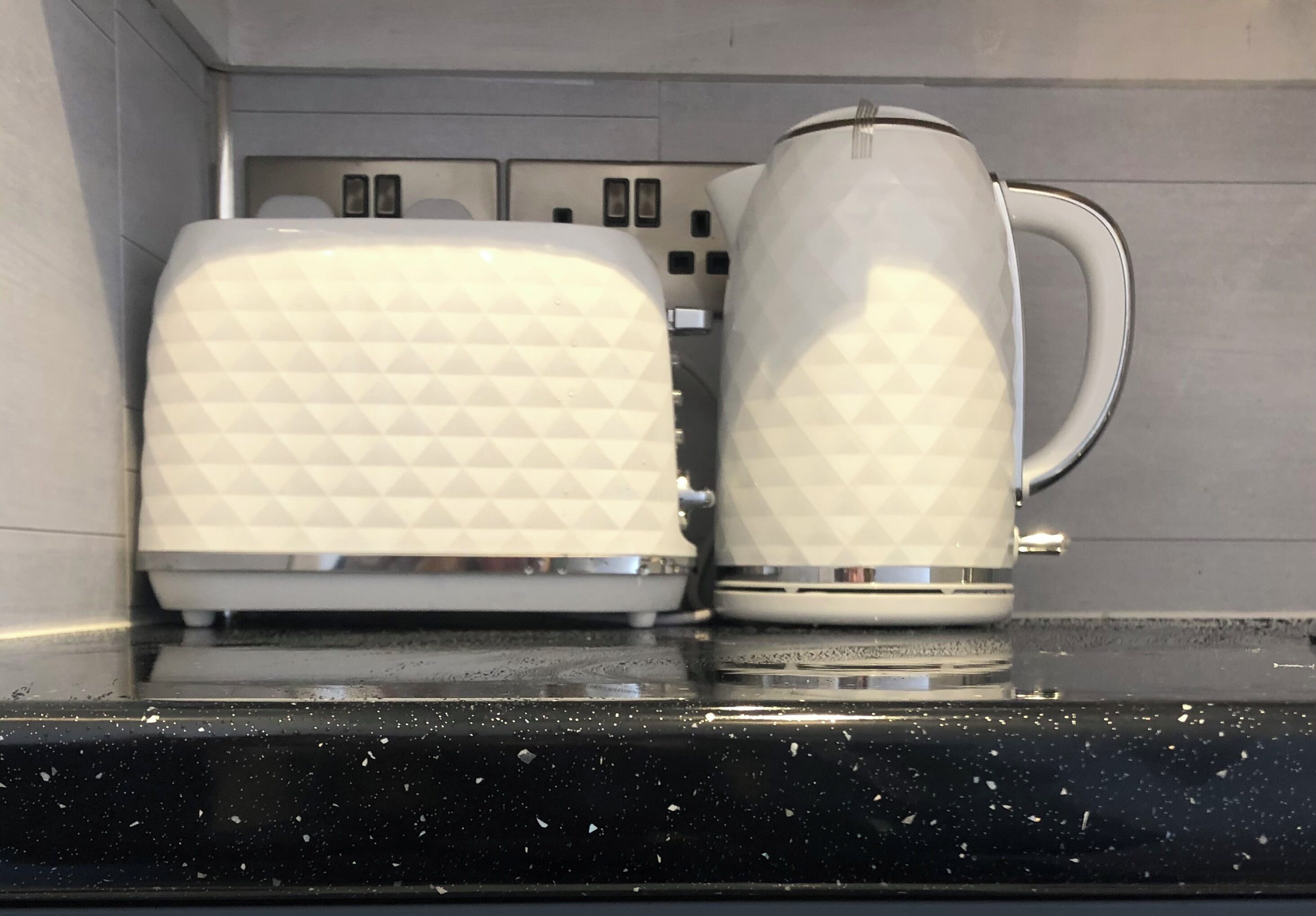 A kitchen counter with a white toaster and a white electric kettle.