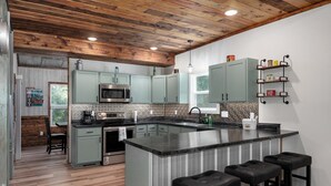 Una cocina moderna con una isla central, taburetes de bar y una lámpara colgante.