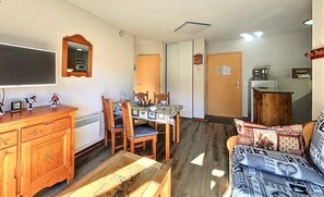 Ein gemütlicher Wohnbereich mit Essplatz, einer Couch, einem Holzkabinett und einem Fernseher.