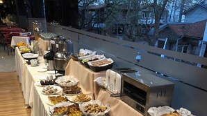 A buffet setup with various food items and utensils, a coffee station, and a view of the outside. - Primacy Hotel (Mar del Plata)