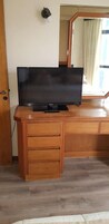 Un escritorio de madera con un televisor de pantalla plana, un espejo y una puerta.