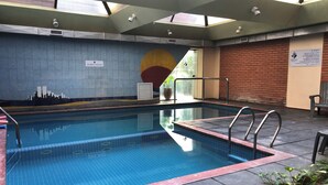 An indoor swimming pool with clear water, surrounded by tiled walls and a brick wall. - Primacy Hotel (Mar del Plata)