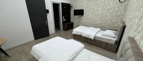 A hotel room with two beds, a TV, and a wardrobe.