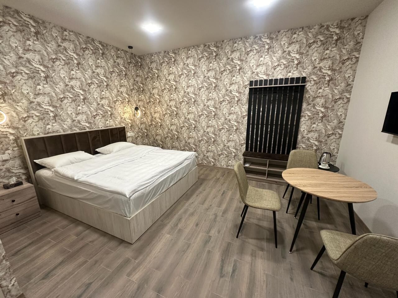 A bedroom with a bed, a desk, and chairs.