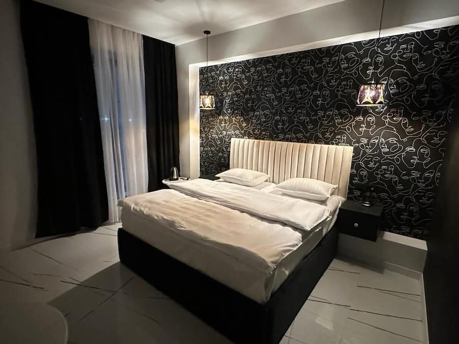 Un dormitorio moderno con una cama grande, un papel tapiz estampado y una mesita de noche con una lámpara.