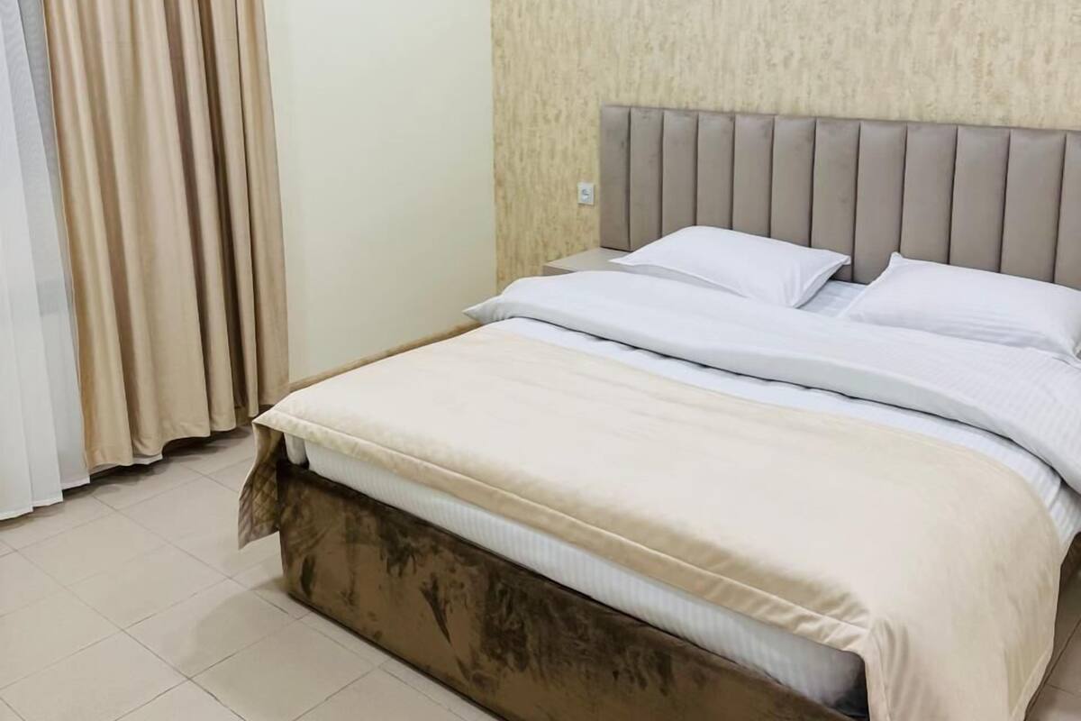 Un dormitorio con cama, cortinas y pared texturizada.